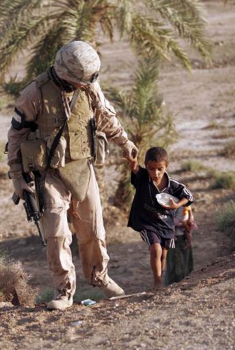 soldier walks with a child in Iraq