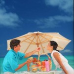 couple-under-beach-umbrella-eating-sunstar