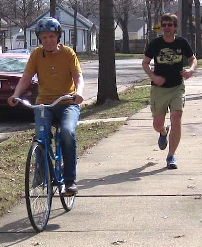 bicycle riding senior with runner on sidewalk-RatRodBikes