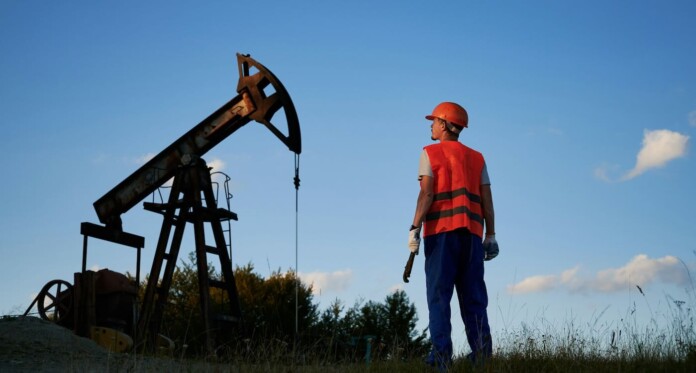 Worker gazes at oil rig energy pump by Getty Images For Unsplash+ HQoFJYL3z1M