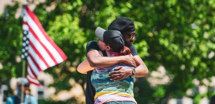 BLM rally bi-racial hug-American flag-love-overcoming-cc-risingthermals