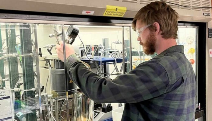 Richard Conk, a graduate student on the project, adjusting teh reaction chamber components - credit BNL/SWNS