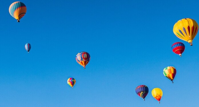 Hot air balloons in blue sky by Raychel Sanner lXwIXXsdhVU-unsplash