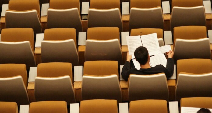 Auditorium seating w student studying writing by Philippe Bout 93W0xn4961g-unsplash