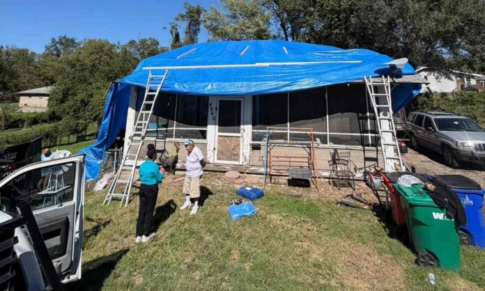 Gilbert Kirk is interviewed amid work by his neighbors to put a tarp on his house roof - credit, Steven Vega, retrieved from Facebook